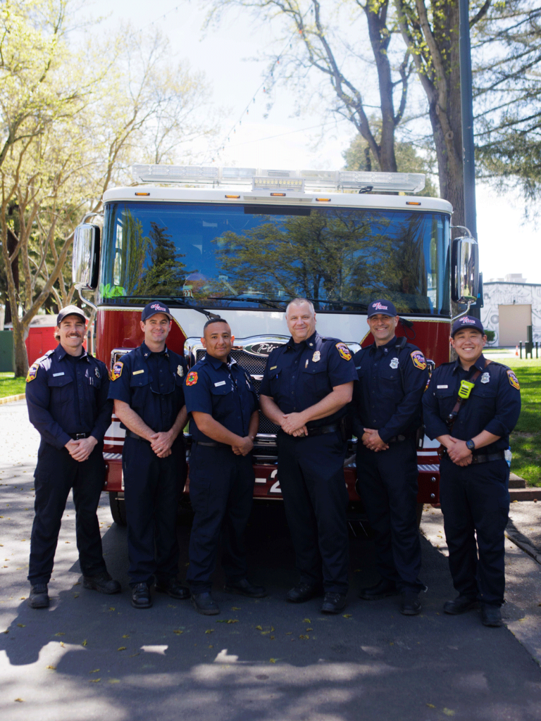 six firefighters posing for photo in front of a fire truck